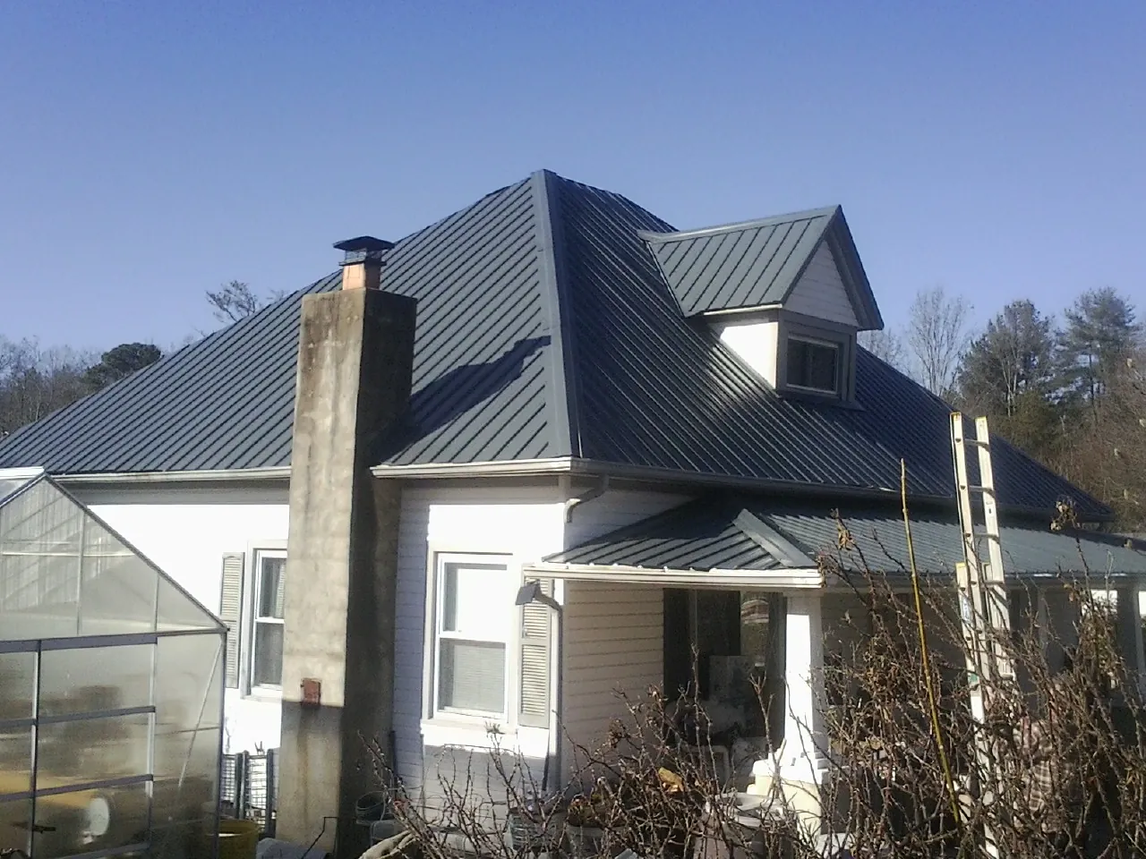 Dark blue standing seam metal roof on a white farmhouse with dormer — Slate & Tile Roof Repair by Roofing Brothers in Hubbardsville
