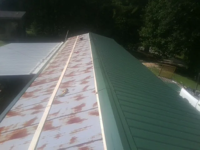 Old rusted panels beside newly installed green metal roofing — Wind Damage Roof Repair by Roofing Brothers in Hubbardsville
