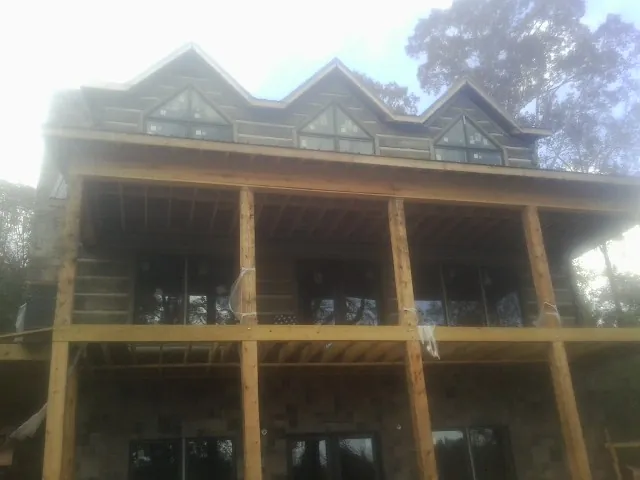 Dormers and porch framing on a large log home under construction — Roof Coating work by our crew in Hubbardsville