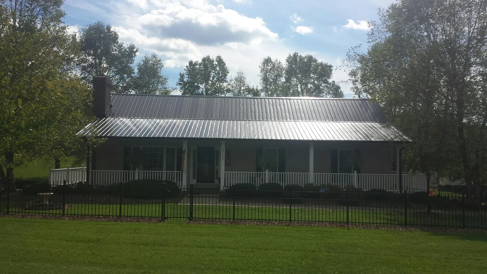 Gray metal roof on a brick ranch with a full width front porch — Gutter Guard Installation work by our crew in Hubbardsville