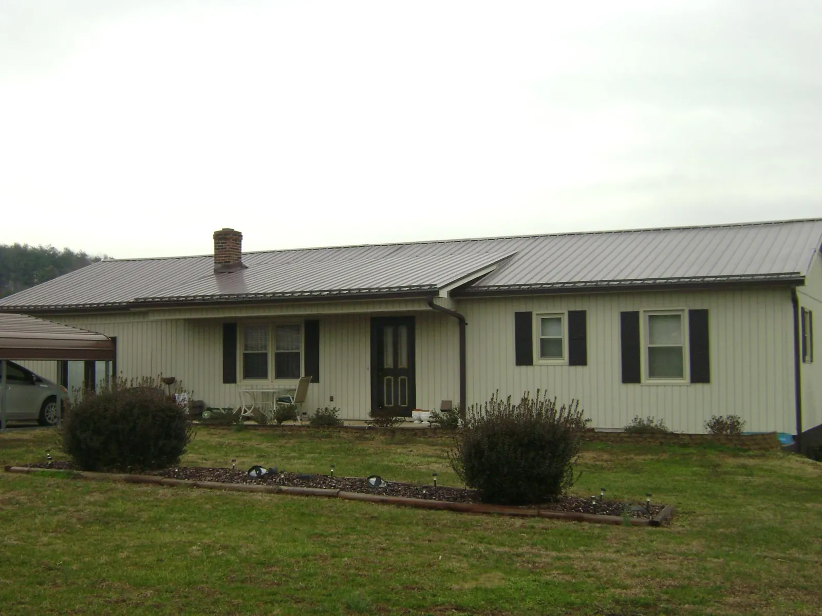 Brown metal roof on a cream sided ranch home with a brick chimney in Hubbardsville