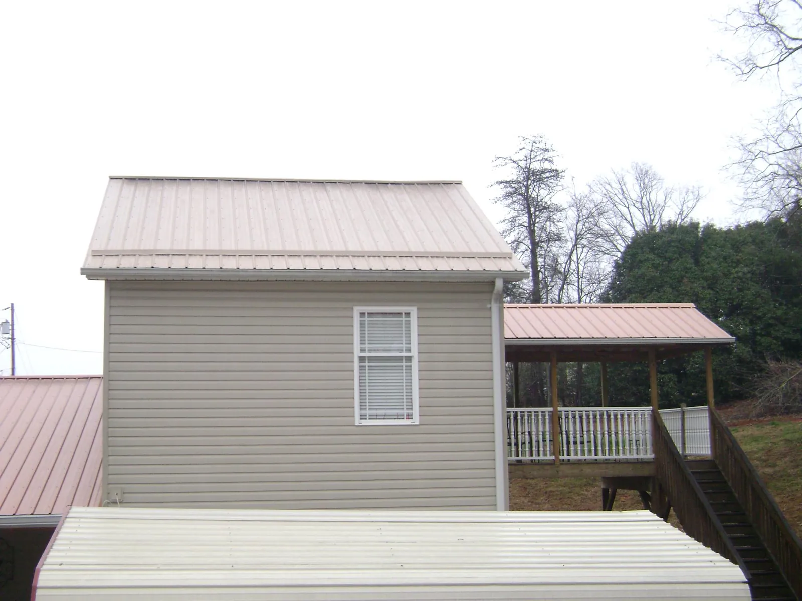 Tan metal roofs on a two story addition and attached porch, from a Roof Replacement job in Hubbardsville