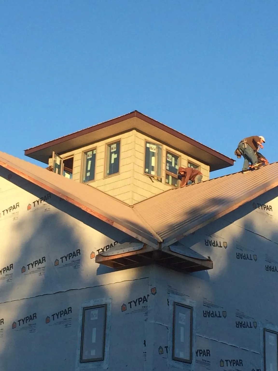 Roofers working around a rooftop cupola on a new metal roof at sunset — Roof Waterproofing in Hubbardsville by Roofing Brothers